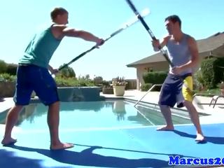 Geý muscular sportsmen sword fighting by the basseýn